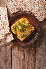 Matzah brei with green onions close-up on a plate. vertical top view
