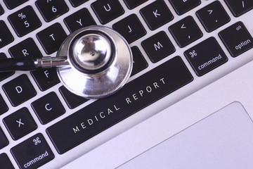 close up of stethoscope and MEDICAL REPORT written on laptop key