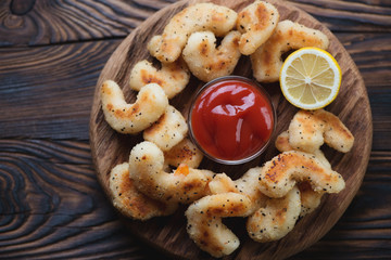 Rustic wooden serving board with fried breaded shrimps, top view