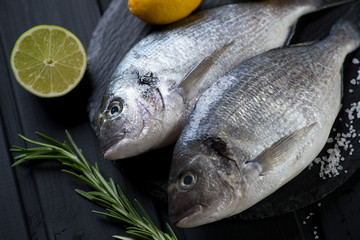 Close-up of two fresh uncooked sea breams and condiments