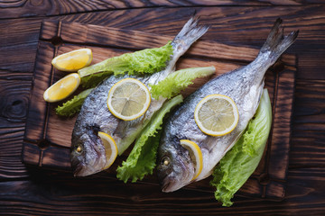 Two whole baked dorados in a rustic wooden setting, top view