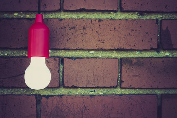Gluehlampe vor Ziegelwand / Einzelne Gluehlampe vor alter Ziegelwand mit Textfreiraum.