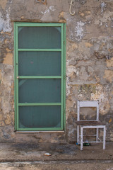 Fototapeta na wymiar Green door of an old house and a chair