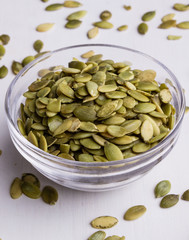 pumpkin seeds on white table with bowl