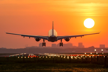 Passenger plane is landing during a wonderful sunrise. - obrazy, fototapety, plakaty