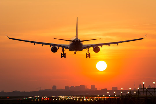Fototapeta Passenger plane is landing during a wonderful sunrise.