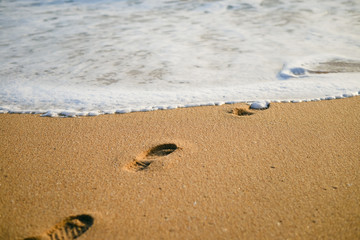 Sunny footprint on the sand and white wave background. swim walk