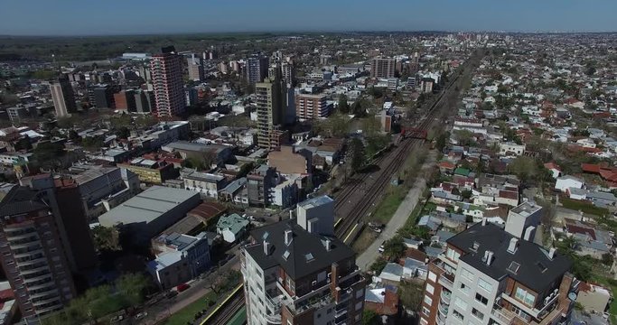 Aerial drone scene of cityscape. Track of train rails breaking the city pattern. Camera travels high in the sky towards train rails. Aerial, panoramic cityscape.