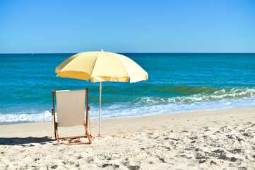 Yellow umbrella and wooden chair on Atlantic sandy beach