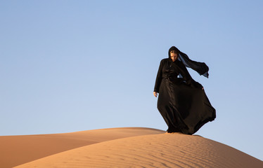 A woman in abaya in sanddunes in Liwa Desert, Aby Dhabi, UAE