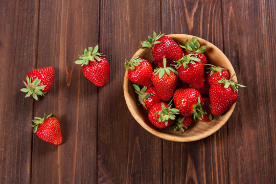 Fresh strawberries on an old wooden surface.