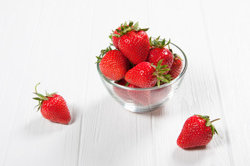 Red fresh strawberry in a bowl on white wooden background