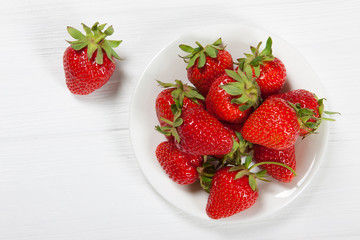 Red fresh strawberry in a bowl on white wooden background