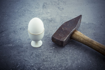 Egg and hammer on stone table. Symbol of strength, force and something hard and unbreakable....