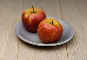 Fresh red Apple sliced on a plate spotted natural wooden background
