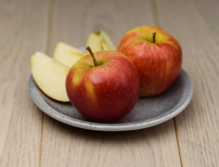 Naklejka na ściany i meble Fresh red Apple sliced on a plate spotted natural wooden background