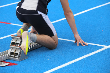muscular athlete in the starting blocks of a athletic track