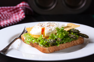 Toasted sandwich with salad leaves, asparagus, cheese and poached egg, closeup