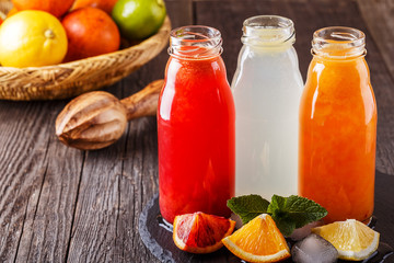 Fresh citrus juices on a dark wooden background.