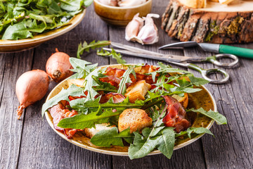 Fresh dandelion salad with fried bacon and garlic croutons.