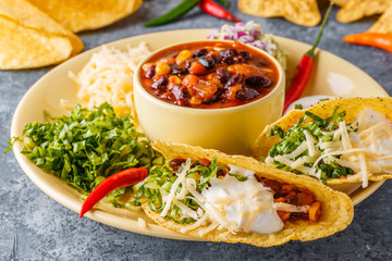 Tacos with chili con carne, salad, cheese and sour cream.