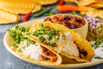 Tacos with chili con carne, salad, cheese and sour cream.