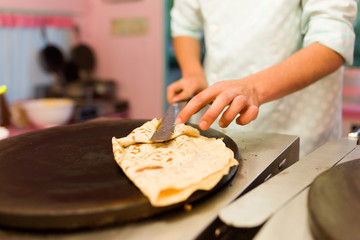 Young man cooking crepes with chocolate in a food truck. - obrazy, fototapety, plakaty