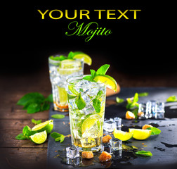 Mojito cocktail on a table. Summer cocktail with rum, lime, mint, ice cubes and brown sugar