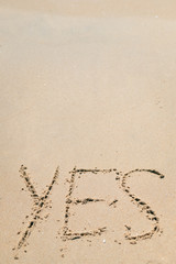 Yes sign written in sand on beach texture top view close up