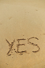 Yes sign written in sand on beach texture sunny background 