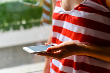 Closeup of female using a smart phone outdoors background.