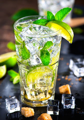 Mojito cocktail on a table. Summer cocktail with rum, lime, mint, ice cubes and brown sugar