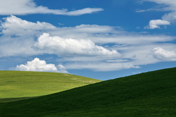 White clouds above green hills