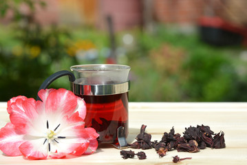 Mug of hot tea hibiscus tea on a background of pine boards 