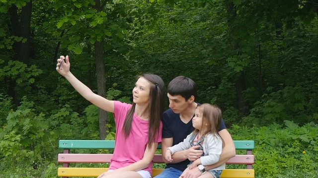 Happy family taking selfie by smartphone in park