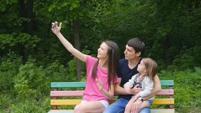 Happy family taking selfie by smartphone in park