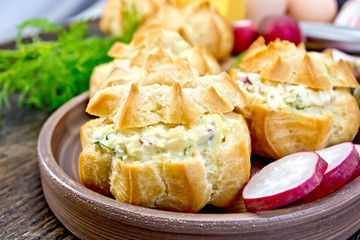 Appetizer of radish and cheese in profiteroles on clay plate wit