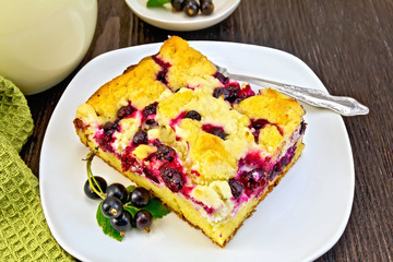 Pie with black currant in plate and fork on board