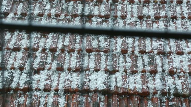 Hailstorm is Crashing onto the Roof of an House in a City.