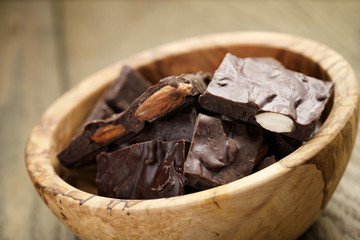 homemade chocolate with almonds in wood bowl, on wood table