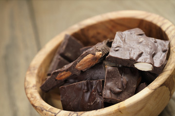 homemade chocolate with almonds in wood bowl, on wood table