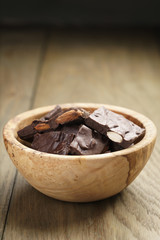 homemade chocolate with almonds in wood bowl, on wood table