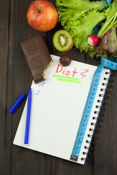 Preparing for the diet program. The decision to initiate dieting. Planning of diet. Notebook measuring tapes and pen on wooden table.
