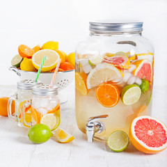 Detox fruit infused flavored water, lemonade, cocktail in a beverage dispenser with fresh fruits