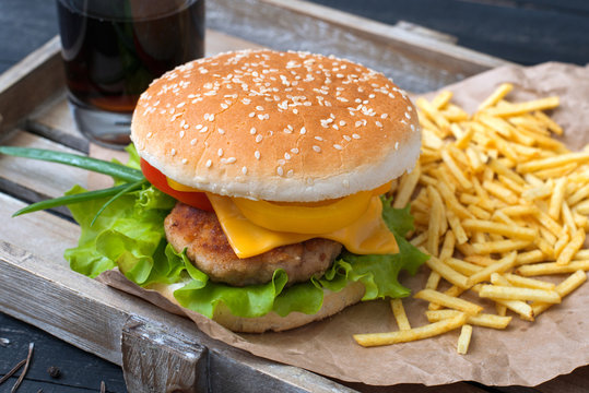Cheeseburger with fries on parchment and Coca Cola