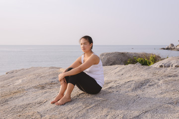Fototapeta na wymiar Young woman sitting at the sea at sunrise