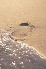 Footprint on the beach sand about to be washed away. 