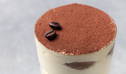Tiramisu, traditional Italian dessert in glass on a grey stone background.