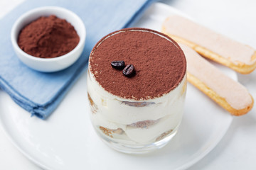 Tiramisu, traditional Italian dessert in glass on a grey stone background