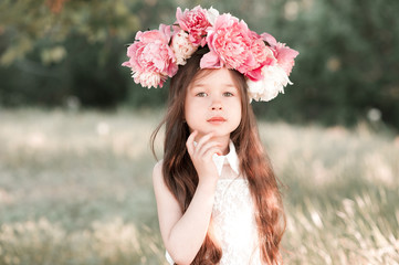 Naklejka premium Cute baby girl 3-4 year old with peony wreath outdoors. Looking at camera. Childhood. 